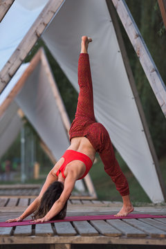 Woman standing in parvatasana one leg pose outdoor on wooden pon