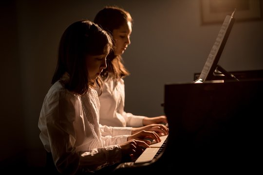 Girls playing piano in music school