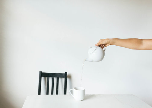 Minimalistic tea setting with hand pouring tea into cup