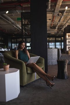 Businesswoman sitting on chair and using laptop