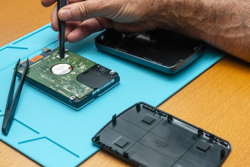 The process of repairing a hard drive by a repairman on a table with special tools