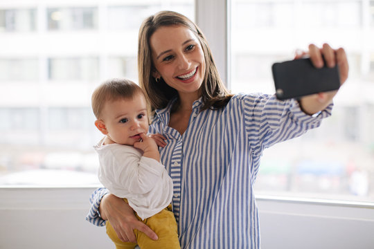 Young mother taking a selfie with her baby at home.