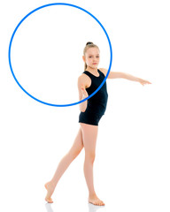 A girl gymnast performs an exercise with a hoop.