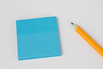 Pencil and sticky notes on a white table. Office accessories for saving notes.