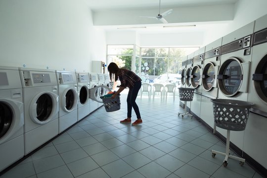 Woman using washing machine at laundromat