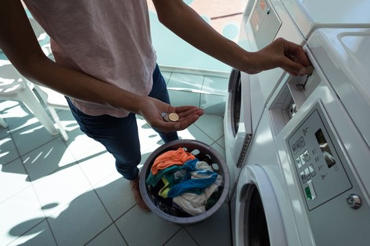 Woman inserting coin in launderette