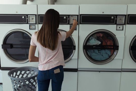 Woman operating washing machine at laundromat
