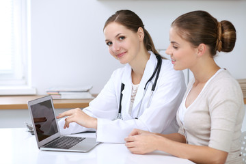 Doctor and patient having a pleasure talk while sitting at the desk at hospital office. Healthcare and medicine concept