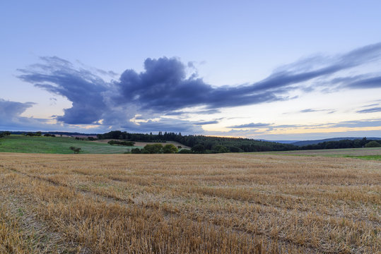 Harvested cereal field at dusk in summer at Roellbach in the Spessart hills in Bavaria, Germany