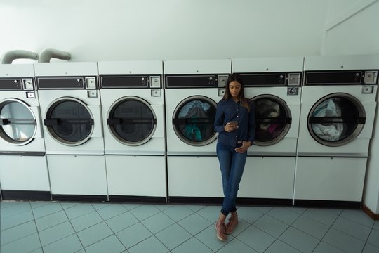 Woman using her phone while waiting at laundromat