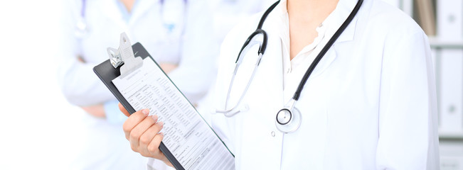 Unknown female doctor with medical staff  at hospital. Teamwork in medicine