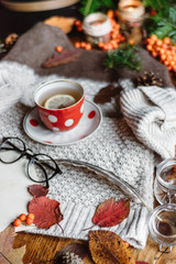 Stylish Flat lay view of autumn leaves and tartan textured sweater on wooden background with cup of tea .  Autumn or Winter concept. 