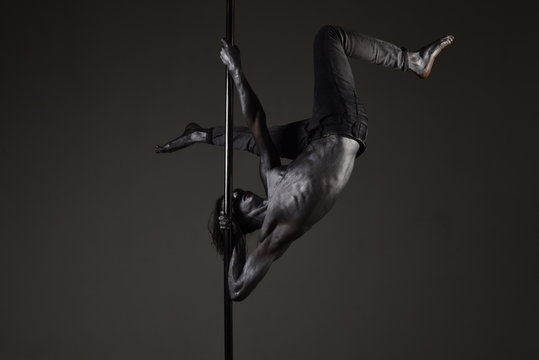 Strong dancer on pole. Freedom. Sexy macho with metal skin. He got the moves. Muscular man with silver body art dancing on pylon. Athletic man make acrobatic elements on pylon. Pole dance sport.