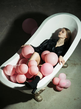 hygiene and spa treatment. woman relax in bath. party balloons in bubbles bath tub. fashion model in autumn coat. having fun in bathroom. Inspiration and wellness concept. health care and beauty.