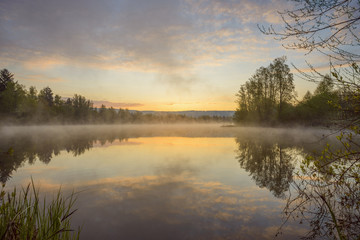 Pastel sky reflected in lake with morning mist at dawn in Mondfeld, Wertheim in Baden-Wurttemberg, Germany