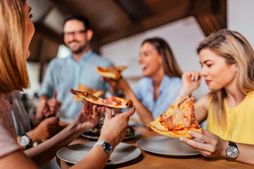 Close-up image of group of friends or colleagues eating pizza. - obrazy, fototapety, plakaty