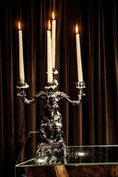 silver candle holder.with candles lit on a table.