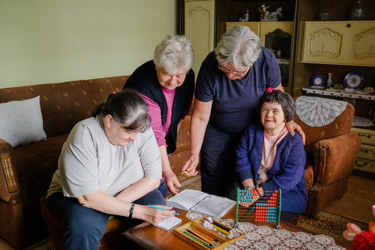Two senior female friends having educational time with caregiver