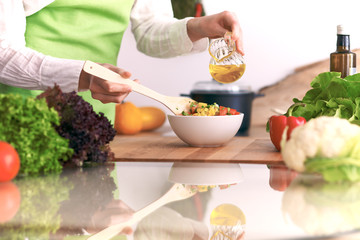 Close Up of human hands cooking vegetable salad in kitchen on the glass table with reflection. Healthy meal, and vegetarian food concept