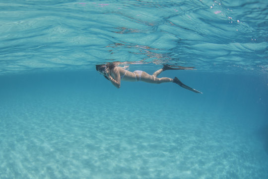 Underwater view of a female tourist snorkeling in clear water in