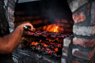 Close-up image of meat kebab cooking on a stone fireplace grill.