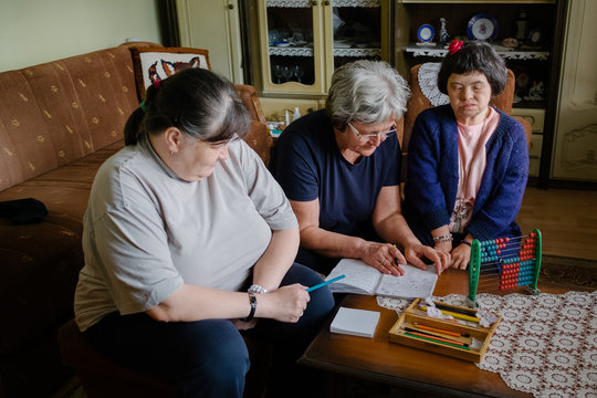 Two senior female friends having educational time with caregiver