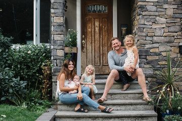Family of five hanging together out on front porch steps in summ