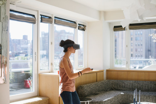 Young woman playing with virtual reality headset at home