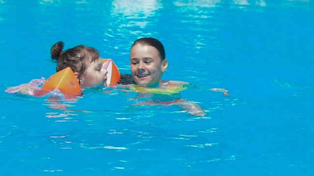 Children swim in the pool. Little girls in the pool.
