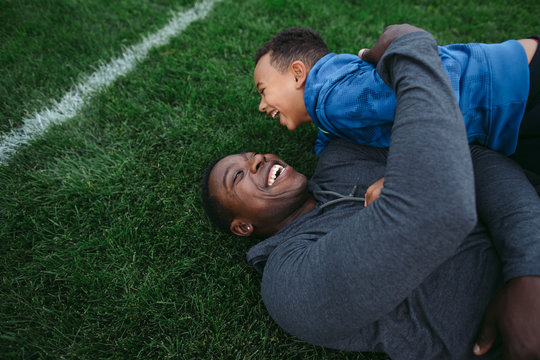 Father and son lying on football field, laughing