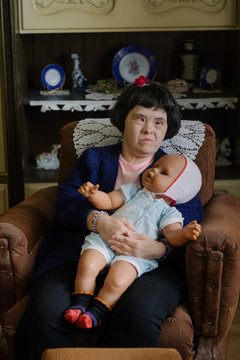 Portrait of a female model with down's syndrome holding her doll