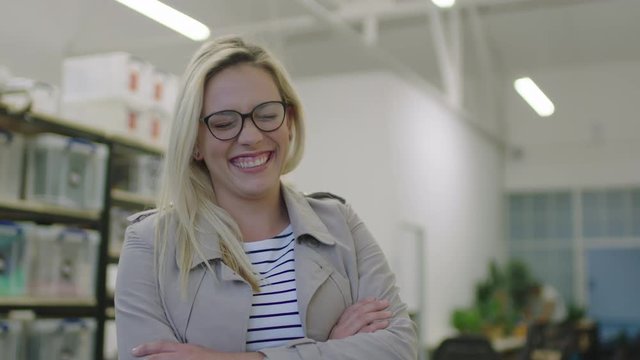 portrait of successful young business woman in startup workspace arms crossed looking at camera laughing cheerful enjoying new career opportunity