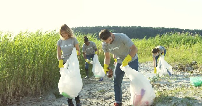 Team of volunteers picking up plastic garbage and trying to keep nature clean at the lake.