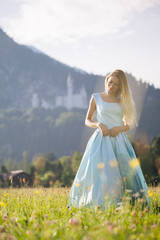Fototapeta na wymiar Blond girl in blue dress infront of the castle