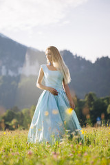 Blond girl in blue dress infront of the castle