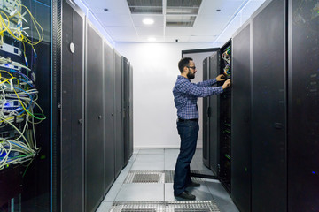 Technician performing maintenance tasks in a server room rack