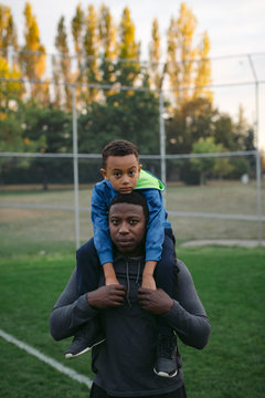 Man and child looking serious at camera during shoulder ride tog