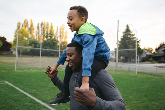 Man and child enjoying shoulder ride together outside in field