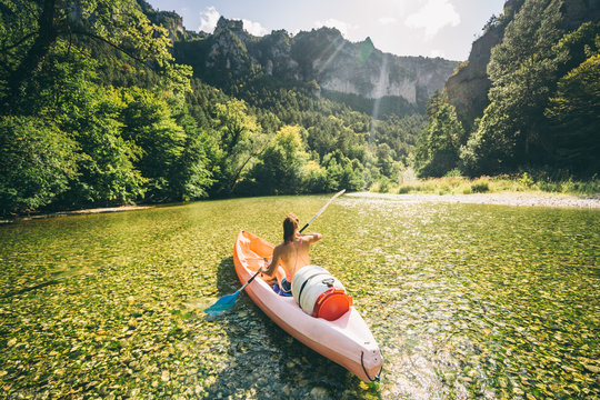 paddler in a canoe on a river in a lush green valley