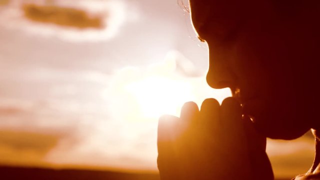 the girl prays. Girl folded her hands in prayer silhouette at sunset. slow motion video. Girl folded her hands in lifestyle prayer pray to God. girl praying asks forgiveness for sins of repentance