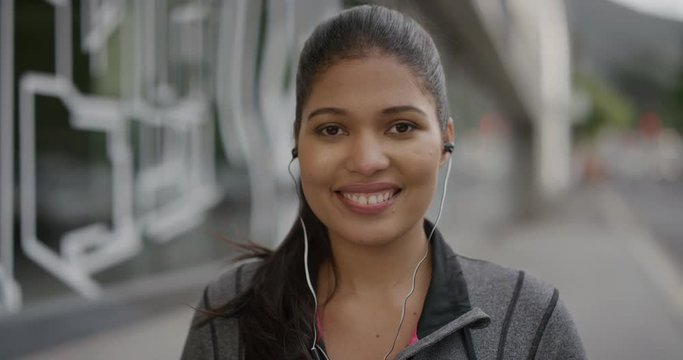 portrait of young woman wearing earphones smiling happy enjoying listening to music in urban city street