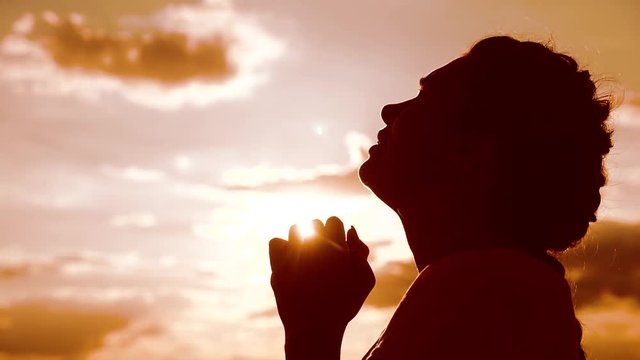 the girl prays. Girl folded her lifestyle hands in prayer silhouette at sunset. slow motion video. Girl folded her hands in prayer pray to God. girl praying asks forgiveness for sins of repentance