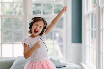 Cute young girl listening to music wearing headphones