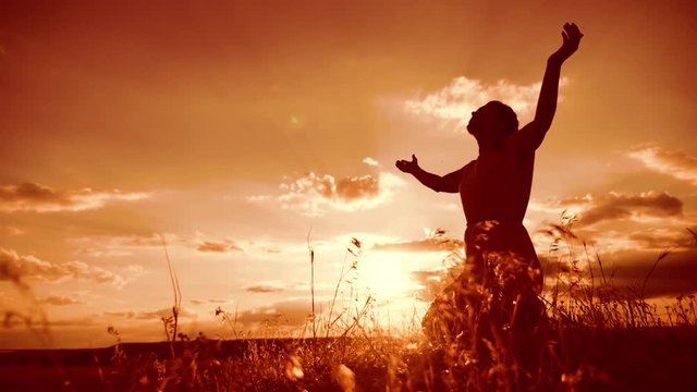 woman praying on her knees. Girl folded her hands in prayer silhouette at sunset. slow motion video. Girl lifestyle folded her hands in prayer pray to God. the girl praying asks forgiveness for sins