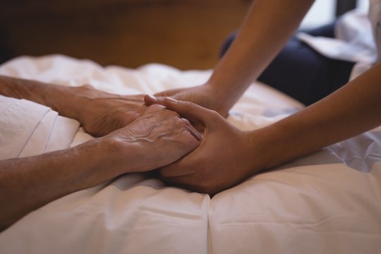 Physiotherapist holding hand of a senior woman