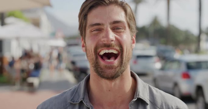 portrait of handsome young man laughing cheerful enjoying warm summer vacation satisfaction on busy urban beachfront gorgeous caucasian male real people series