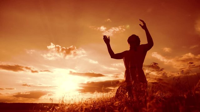 Girl folded her hands in prayer silhouette at sunset. woman praying on her knees. slow motion video. Girl folded her hands in lifestyle prayer pray to God. the girl praying asks forgiveness for sins