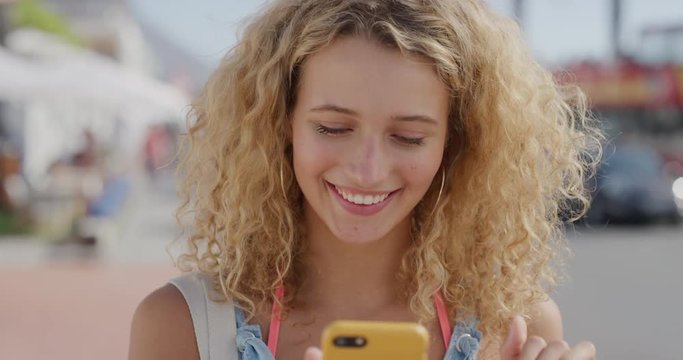 portrait of happy beautiful blonde woman using smartphone enjoying texting browsing on summer vacation sharing experience online attractive female tourist beachfront