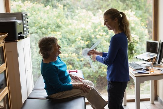 Physiotherapist showing goniometer reading to senior woman - Powered by Adobe