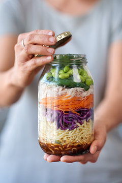 hands holding glass jar filled with fresh colourful vegetables